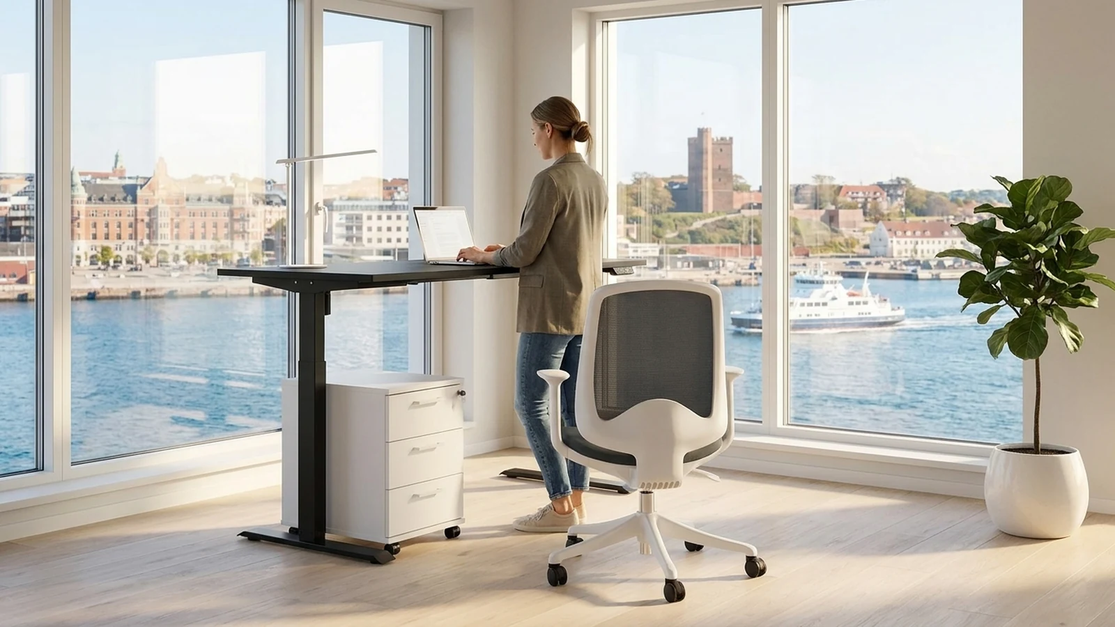Arbetsplats med svart höj- och sänkbart skrivbord, stol och förvaring, utsikt över Sundet i Helsingborg